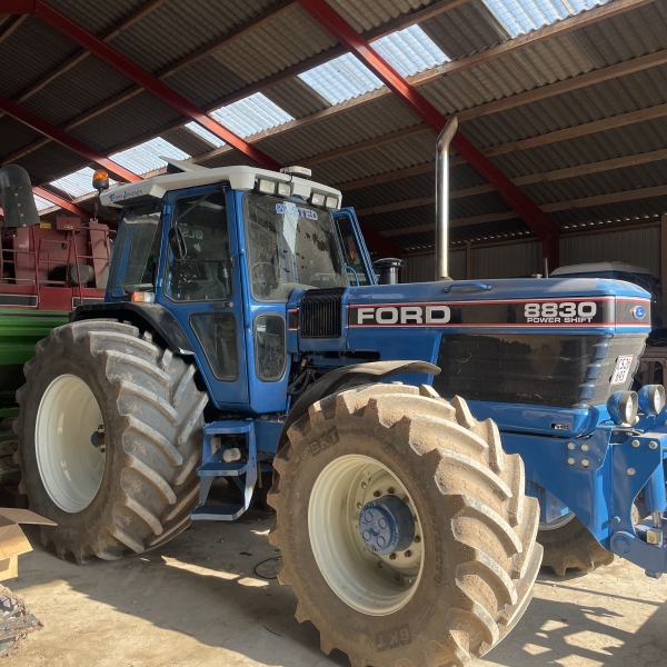 Blå Ford 8830 traktor parkeret i en lade.