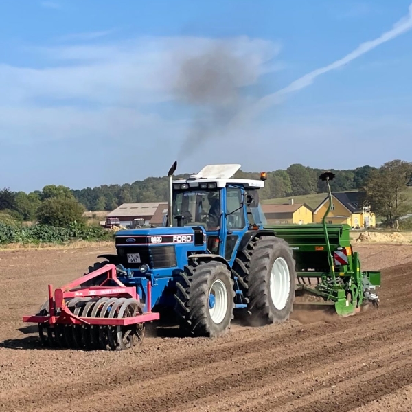 Traktor med såmaskine i brug på en mark.